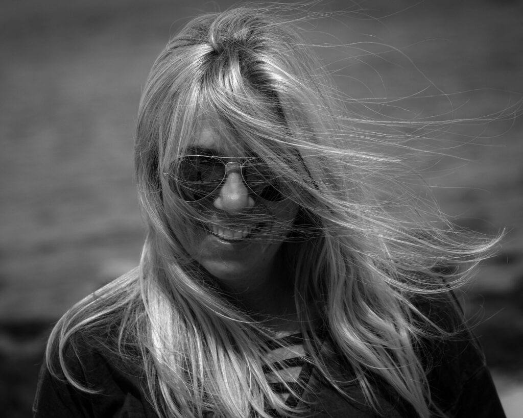 Porträt von Diane K. Senft mit Sonnenbrille, Wind im Haar, outdoor.