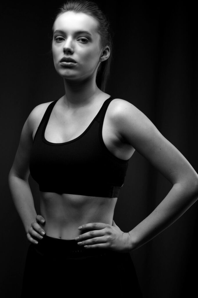 Schwarz-Weiß-Porträt einer jungen Frau in Sportkleidung, selbstbewusst und stark.