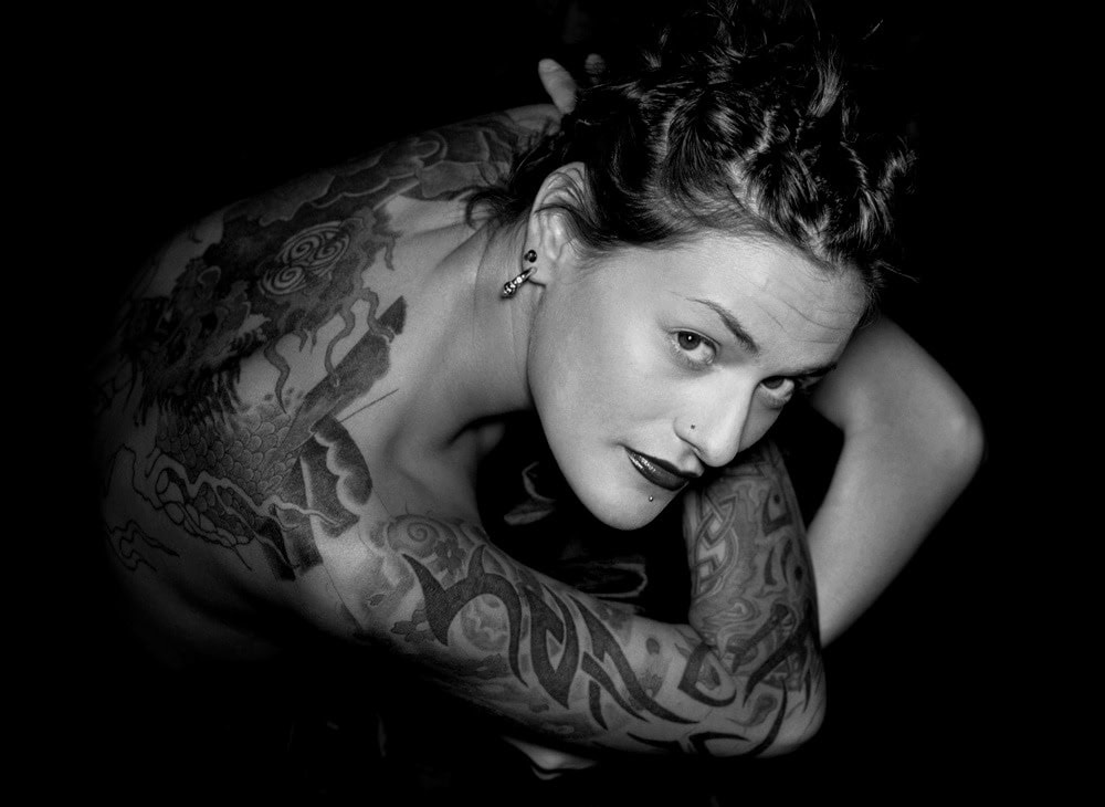 Porträt von einer Frau mit Tattoos und intensivem Blick.