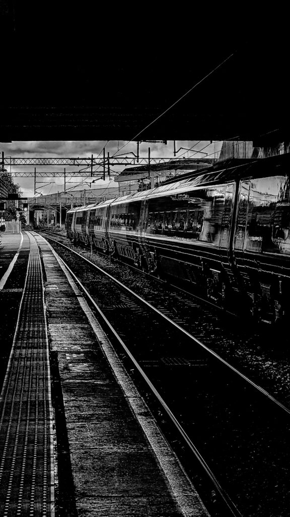 Schwarz-Weiß-Foto eines Zugs an einem Bahnhof bei Nacht.